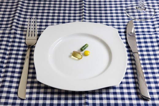 Assiette avec des gélules et comprimés de compléments alimentaires, symbolisant les dangers des abonnements trompeurs en ligne.