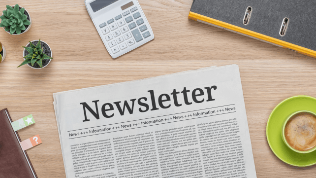 Vue d’un bureau organisé avec une newsletter imprimée au centre, entourée d’objets de travail, illustrant la communication et la collecte d’avis pour améliorer l’expérience utilisateur.