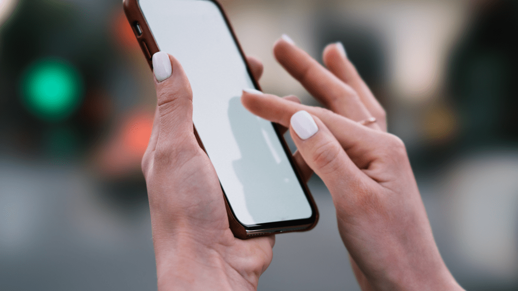 Deux mains interagissant avec un smartphone dans un décor urbain nocturne, illustrant l’usage quotidien des forfaits mobiles et les enjeux liés aux droits des consommateurs.