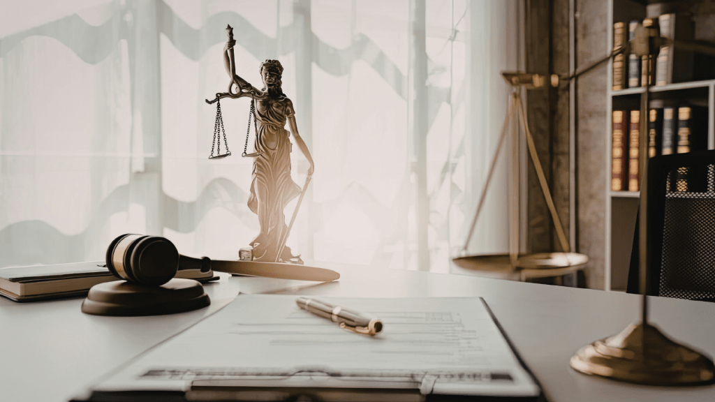 Bureau juridique avec statuette de la Justice, marteau de juge et documents, illustrant les démarches de règlement amiable et les procédures civiles.