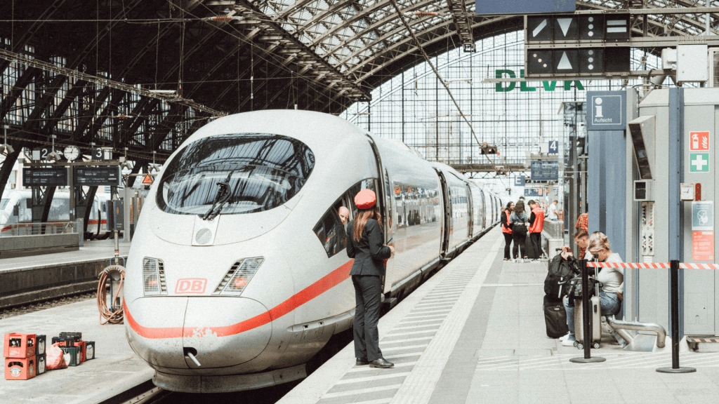 Agent ferroviaire aidant une voyageuse à bord d’un train dans une grande gare moderne, illustrant le service d’assistance en gare et les difficultés rencontrées par les personnes handicapées lors de leurs déplacements.