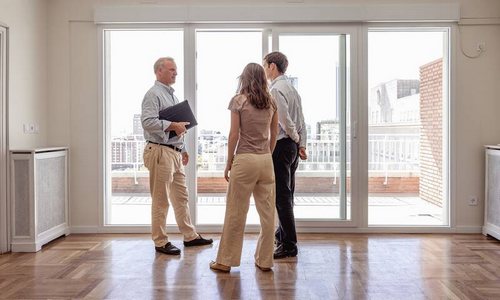 Trois personnes visitant un appartement lumineux, illustrant les difficultés d’accès au logement et les enjeux de pouvoir d’achat.